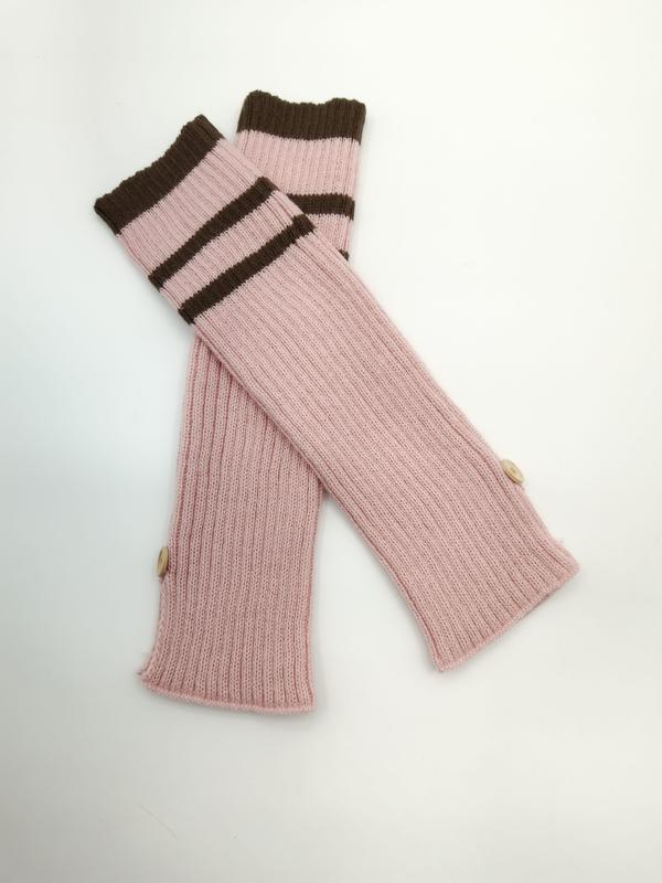 Roze geribde armwarmers zonder vingers met bruine gestreepte manchetten en houten knopen op witte achtergrond.