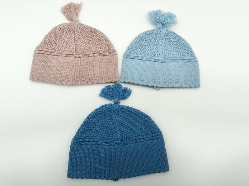 `Drie gebreide babymutsen met pompon in roze, lichtblauw en blauwgroen op witte achtergrond, 3-pack`