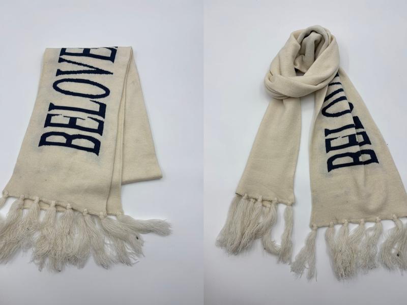 Crème gebreide sjaal met marineblauw BELOVED-intarsia-opschrift en lange franjes, plat en omgeslagen getoond.