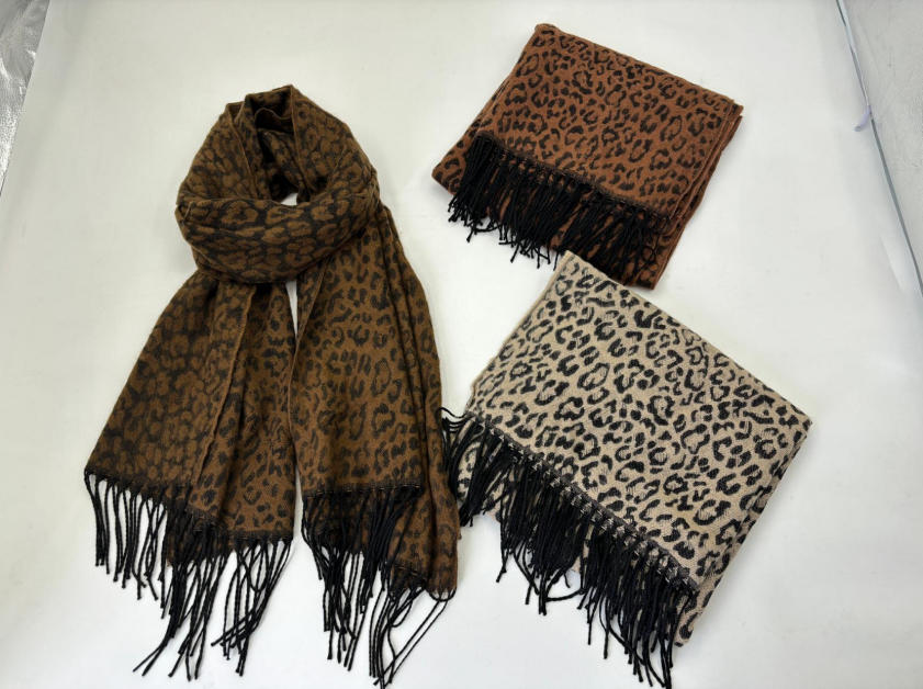 Drie luipaardprint sjaals met zwarte franje in donkerbruin, karamelbruin en beige, plat op witte achtergrond.