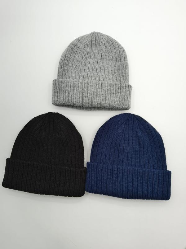 Drie geribbelde gebreide beanie mutsen in lichtgrijs, zwart en marineblauw, plat gelegd op witte achtergrond.