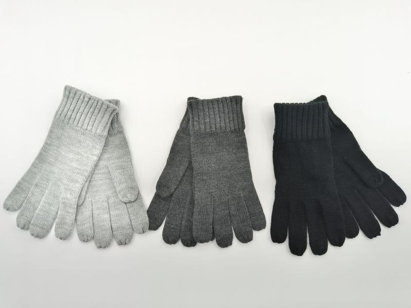 Drie paar geribbelde gebreide winterhandschoenen in lichtgrijs, antraciet en zwart, plat neergelegd op witte achtergrond.