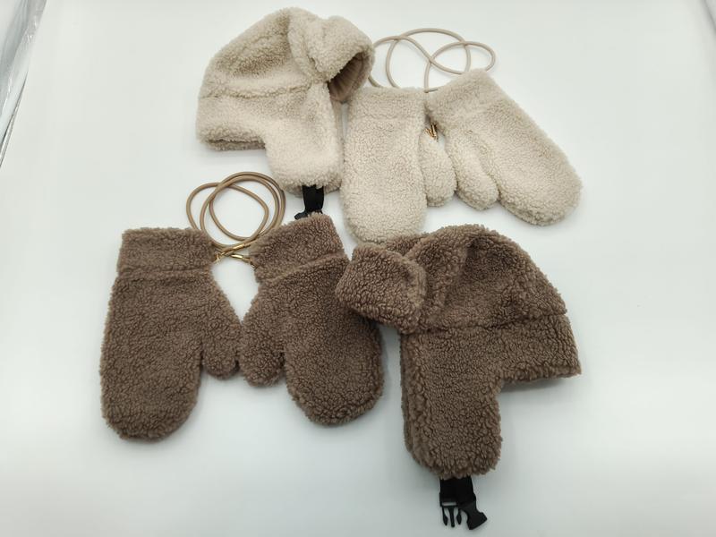 Crème en bruine sherpa fleece muts met oorflappen en wanten, verbonden door elastieken koordjes, in twee maten.